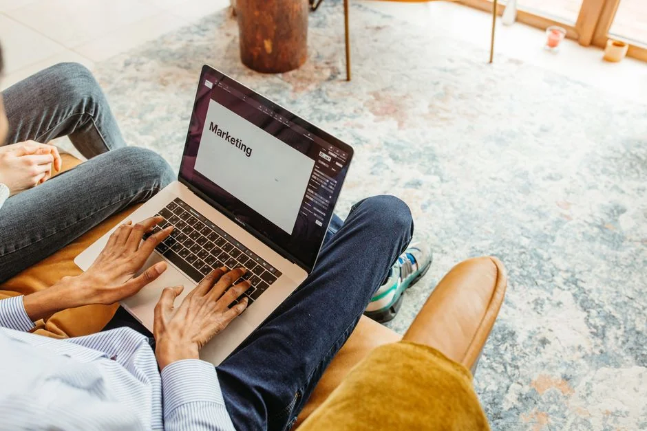 A modern workspace showing hands analyzing marketing data on a laptop and paper documents.